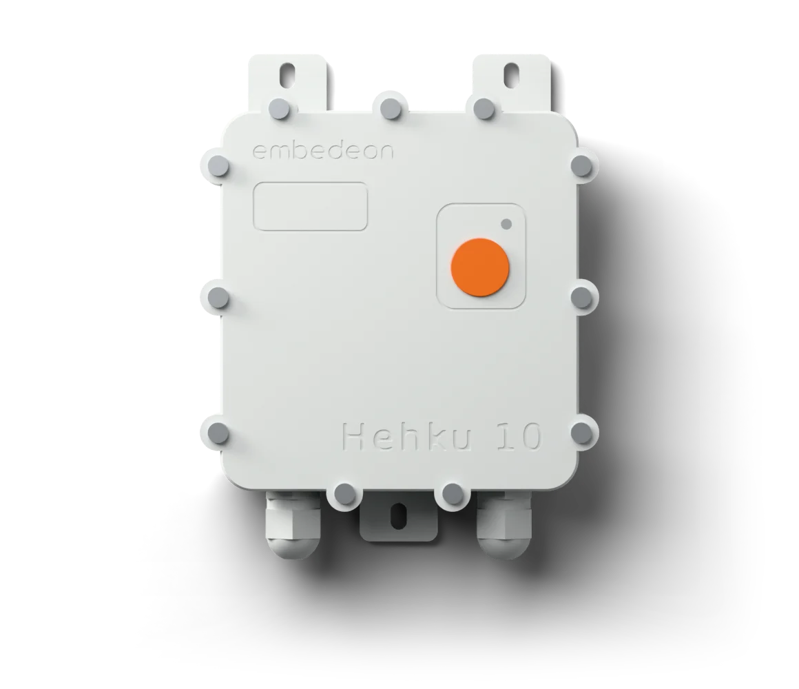 Hehku&nbsp;10 seen from the front: a light grey housing with an orange setup button, two cable glands underneath and mounting tabs above and below